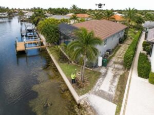 Aerial surveyor mapping a waterfront property, seawall, dock, side-yard access, and shoreline conditions in West Palm Beach, Florida.