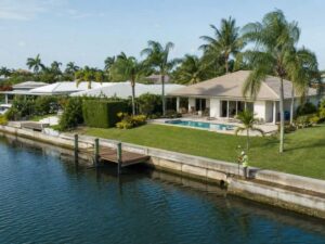 Boundary surveyor checking a canal-front property boundary near a seawall and dock in West Palm Beach, Florida.