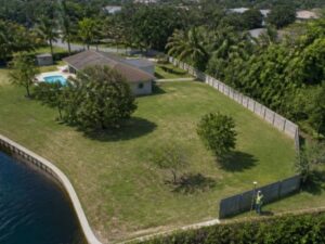 Land surveyor mapping an irregularly shaped canal-side parcel with multiple boundary edges in West Palm Beach, Florida.