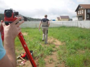 Surveyor measuring vacant land before property development. 